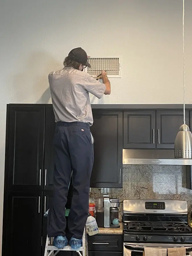 Technician inspecting an air vent during HVAC service in Sky Lake